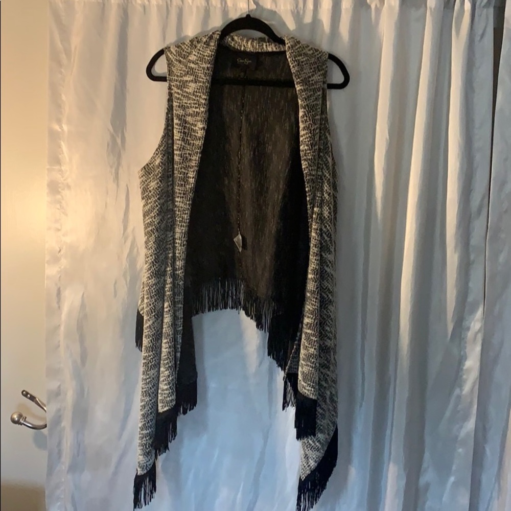 Black and white sweater vest with tassels.